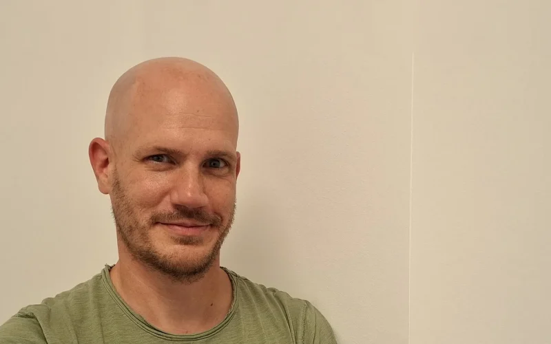 René Nossek, Heilpraktiker in Bonn-Lessenich, lächelt in seiner Praxis