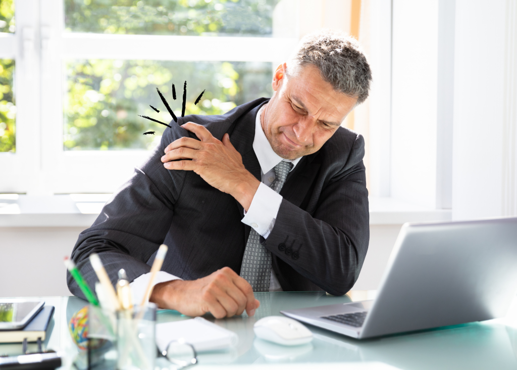 Mann mit Schulterschmerzen sitzt vor PC.